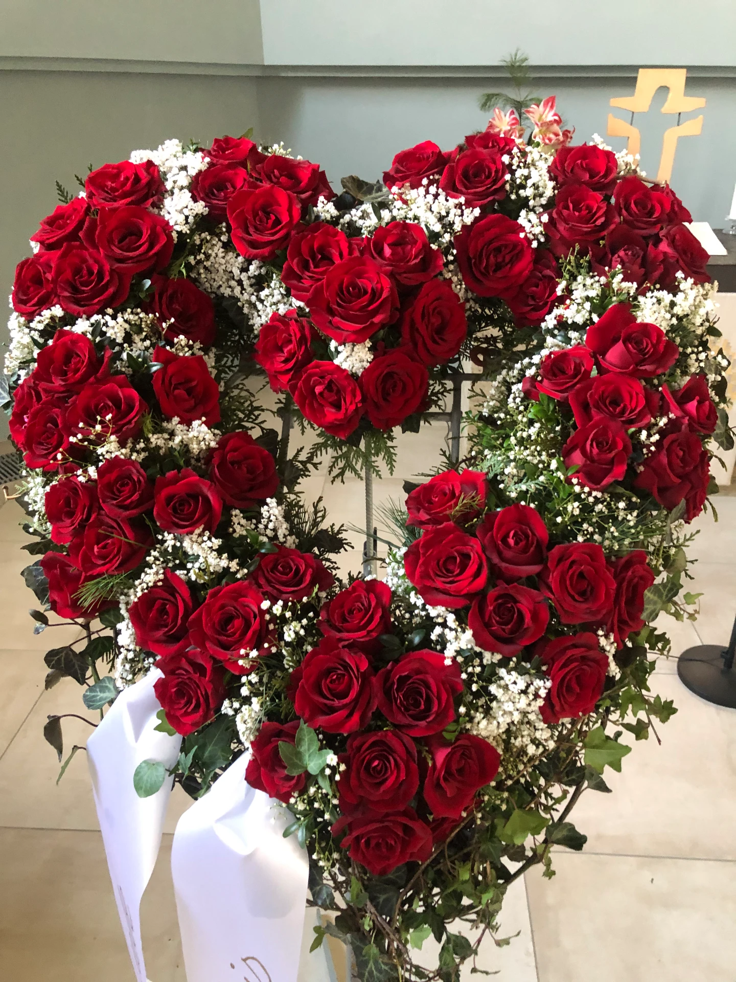 Großes herzförmiges Trauergesteck aus roten Rosen und Schleierkraut