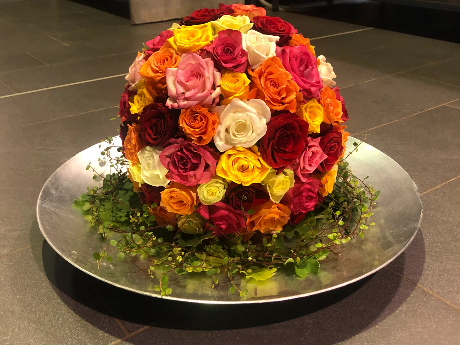 Kugelförmiges Trauergesteck aus Rosen in Rot, Orange, Gelb, Rosa und Weiß