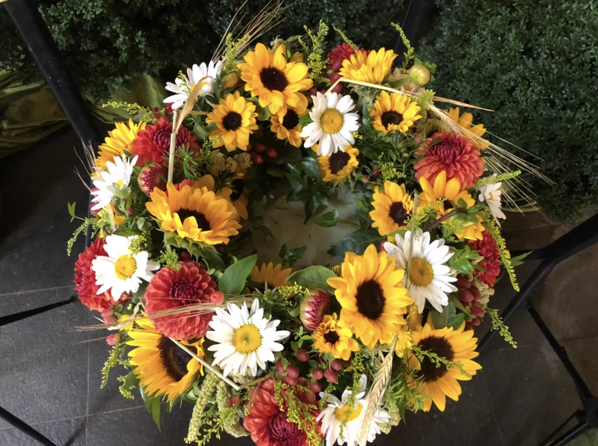 Runder Blumenkranz mit Sonnenblumen, Margeriten und roten Dahlien