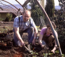 Historisches Farbfoto: Martin Höfer pflanzt gemeinsam mit einem Mädchen Jungpflanzen im Beet