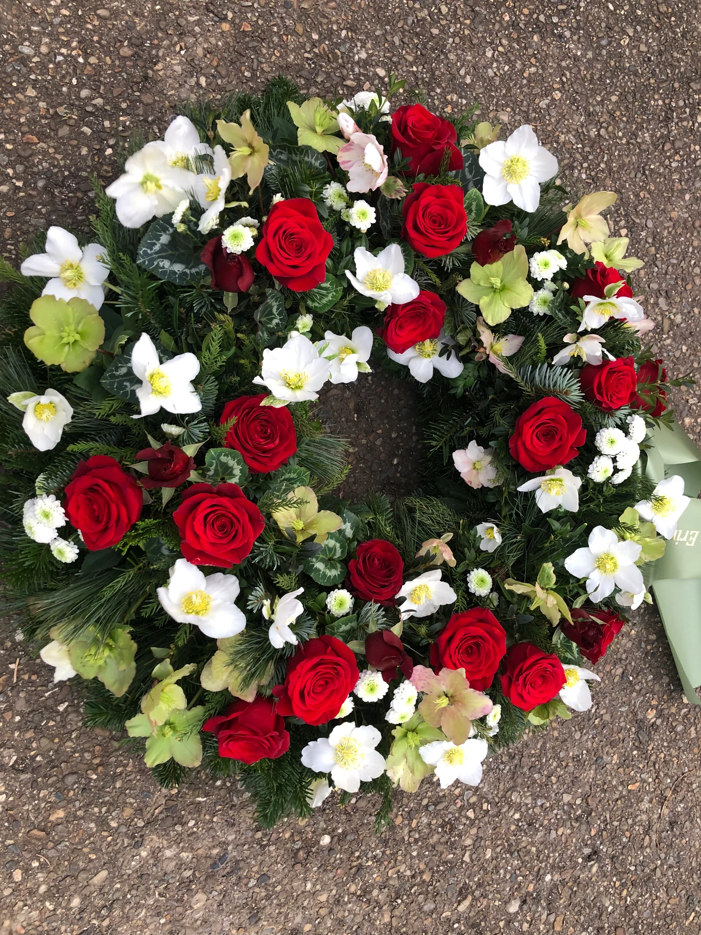 Runder Trauerkranz mit roten Rosen, weißen Christrosen und Tannengrün